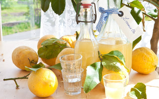 Homemade Limoncello bottles with lemons around and  small drinking glasses