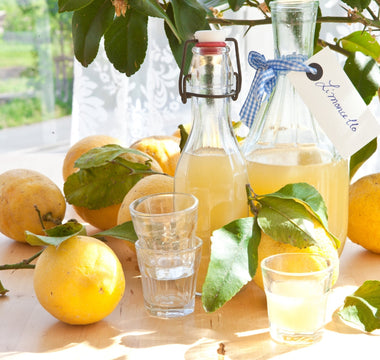 Homemade Limoncello bottles with lemons around and  small drinking glasses